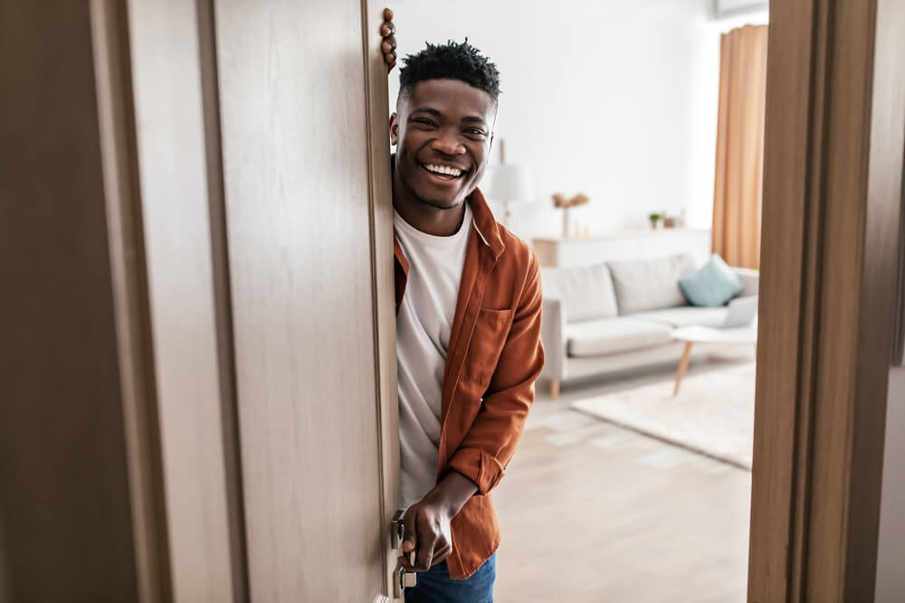 Male Opening Door Of His New House Smiling To Camera And Welcoming You To Apartment