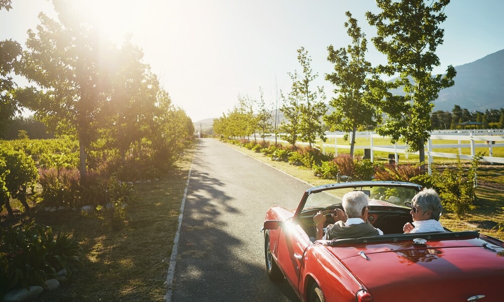 older retired couple in a red convertible driving near a vineyard_mandatory minimum car insurance in Canada