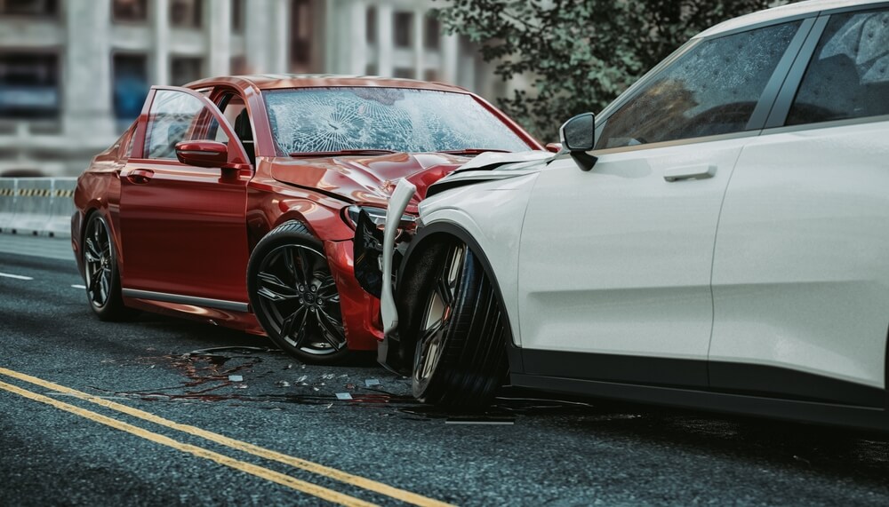 one red car and a white car engaged in a head-on collision on a city street