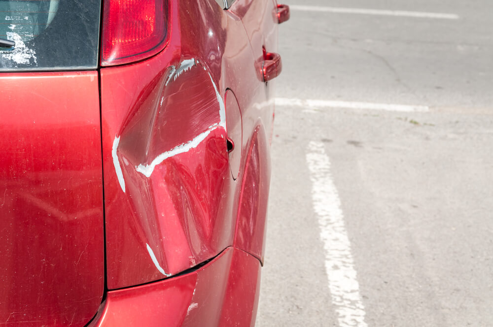 the dented back bumper of a red car with the at-fault driver gone