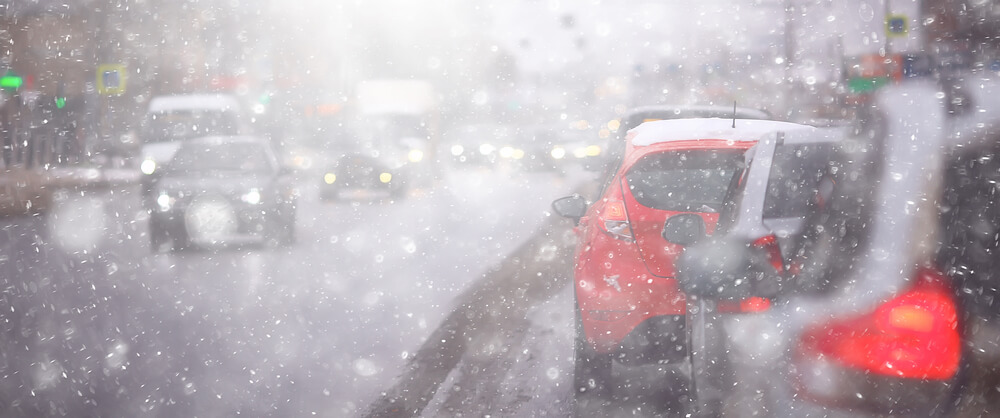 winter driving in the city surrounded by traffic with low visibility with a red car a few cars ahead