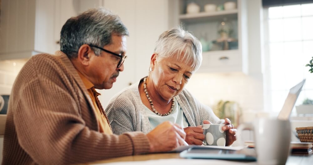 Laptop, finance and senior couple in home for budget, taxes and mortgage payment. Retirement, marriage and man and woman with paperwork for life insurance, investment and bills for online banking