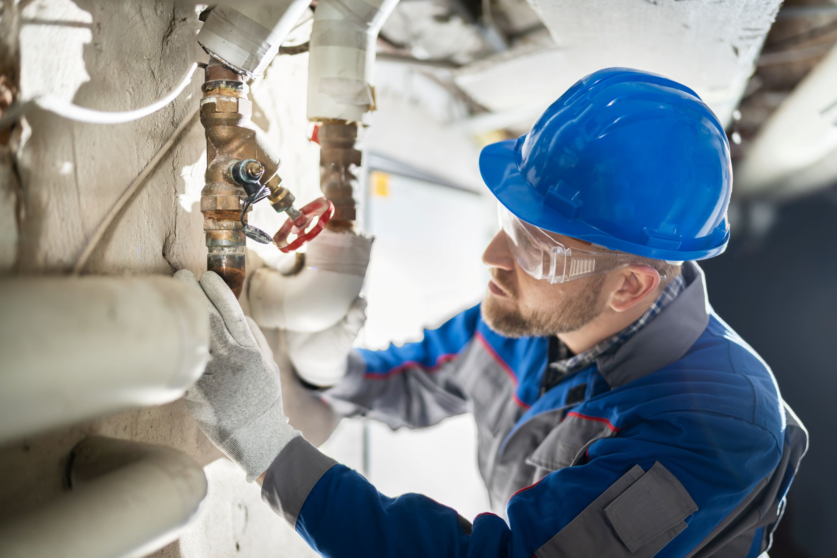 Male worker inspecting water valve for leaks in basement