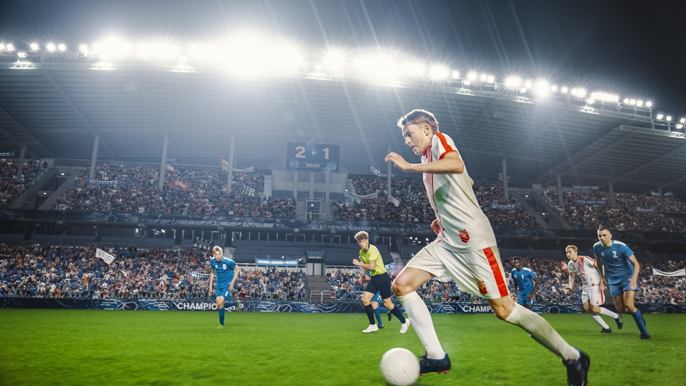 Soccer match Caucasian male player forward dribbles in stadium as fans cheer