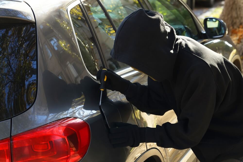 Thief with screwdriver opening fuel cap. Car hijacking