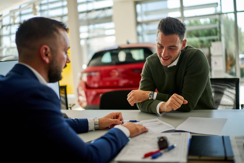 Car salesman and a customer engage in a discussion at a dealership table