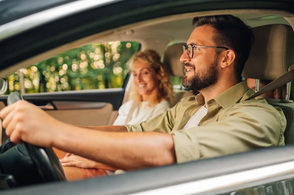 Father driving a car and traveling with his wife and daughters on a weekend trip away from the city