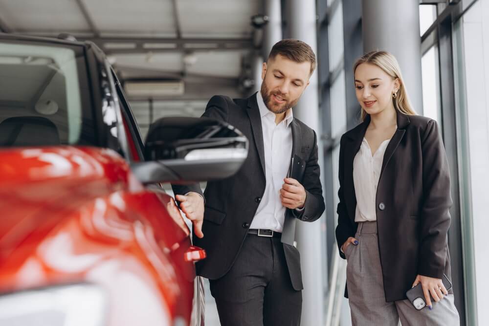 Car Sales Manager Showing Red Car To Woman