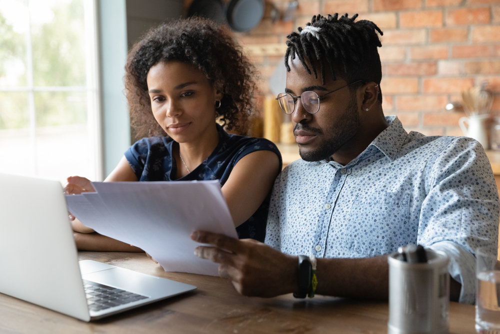 Millenial Black Couple Planning Family Budget in Home on Laptop