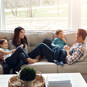 Family relaxing on a couch in a sunlit living room.