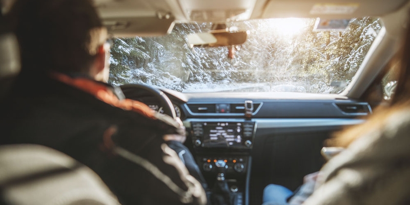 A driver and passenger look out at the snowy road