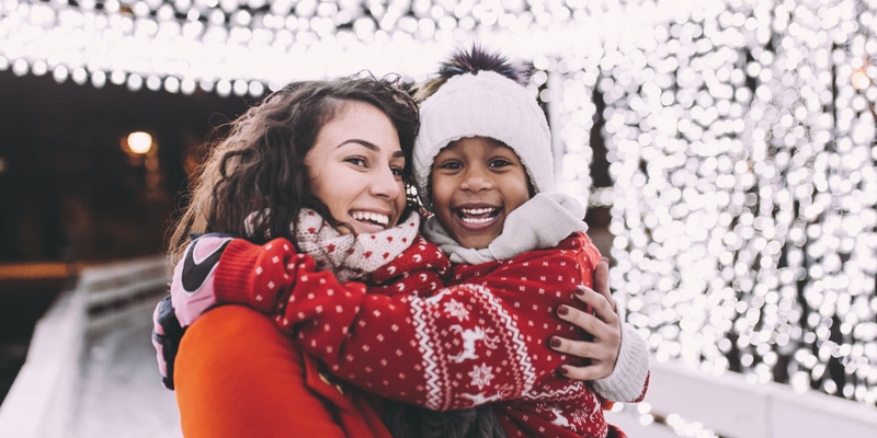 A mother holds her child and they smile in a tunnel of lights