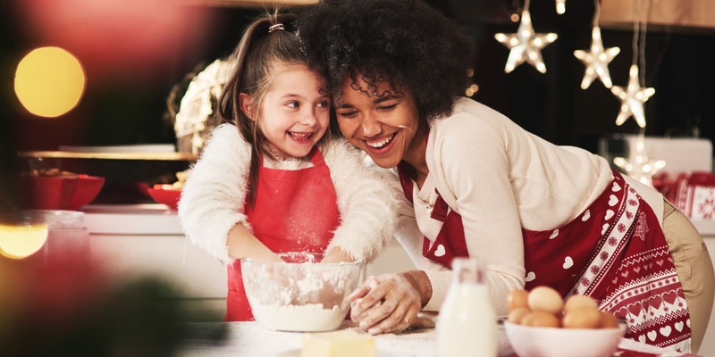 A woman and child bake together with star lights in the background