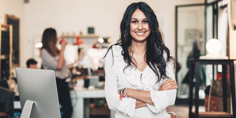 A woman crosses her arms smiling at her business