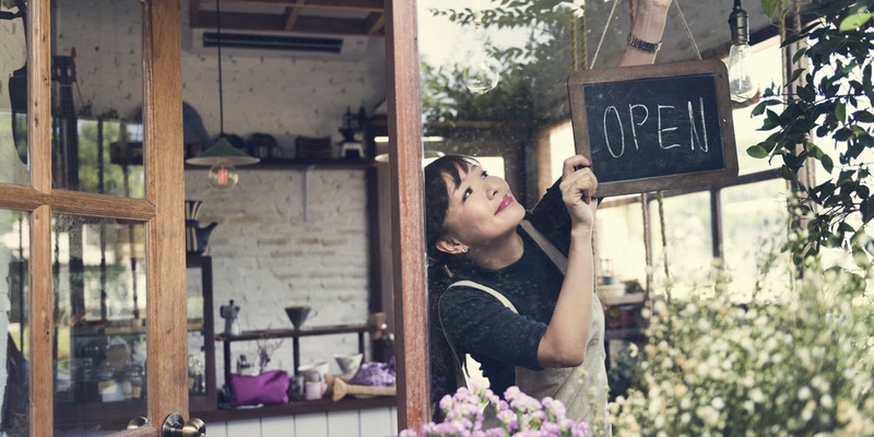 An employee flips the open sign in the window