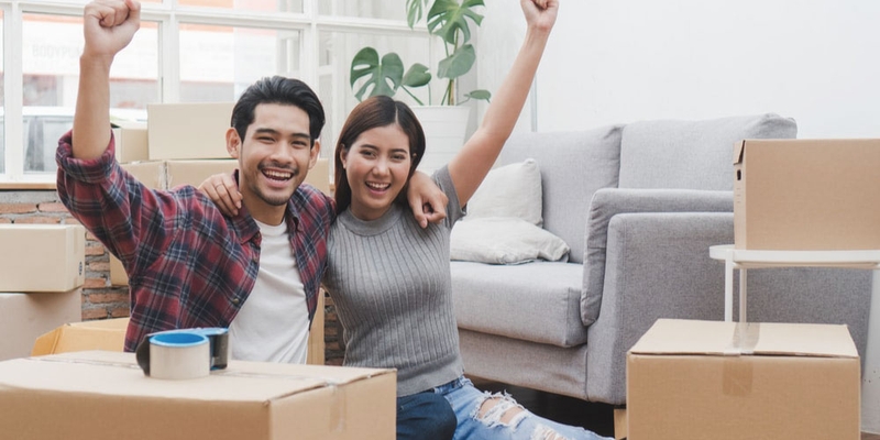 A happy couple sit amongst boxes in their new apartment