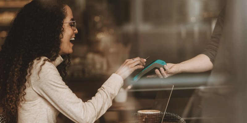 A woman pays with something via tap at downtown cafe