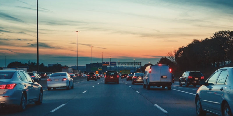 Several lanes of traffic on a highway during dusk