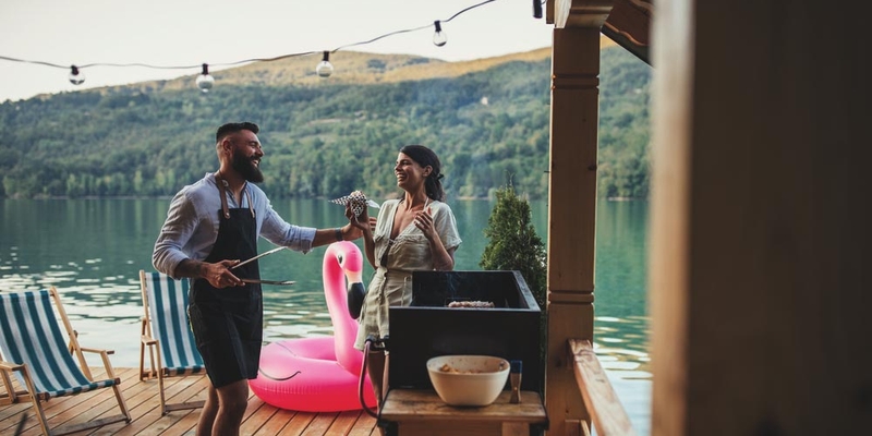 Man and woman laughing by bbq on the lake