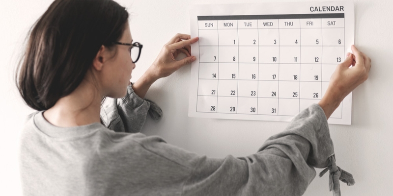 A woman pins a calendar to the wall
