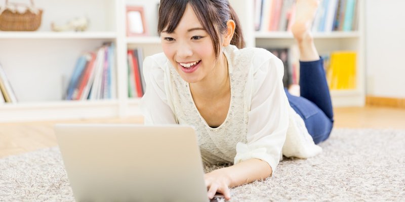 Woman laying on her stomach while browsing her computer 