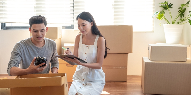Young Asian married couple helping unpacking and checking items together and woman checking stuff by using checklist.jpg