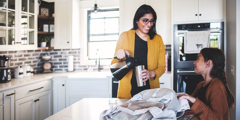 Mom pours herself a coffee while daughter packs her school bag in the morning