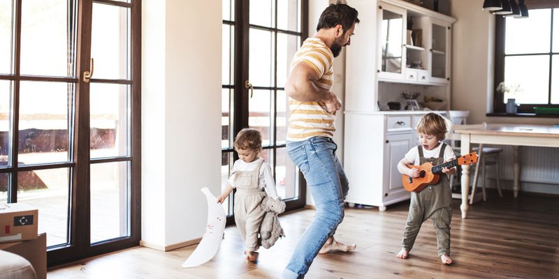Daddy and his two toddlers rock out in the kitchen as toddler plays a tiny ukulele