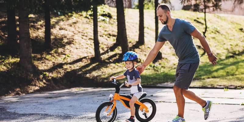 Dad helps his son learn how to ride a bike