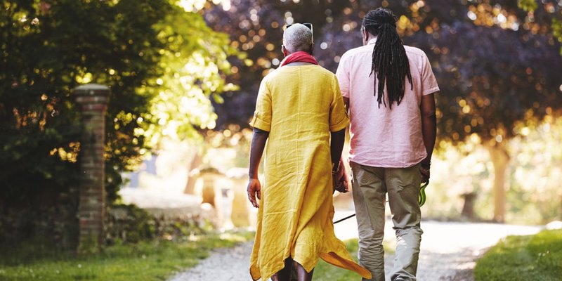 Grown man walking with his mother down a quiet street road