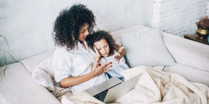 mom and daughter snuggle on couch in bright modern living room