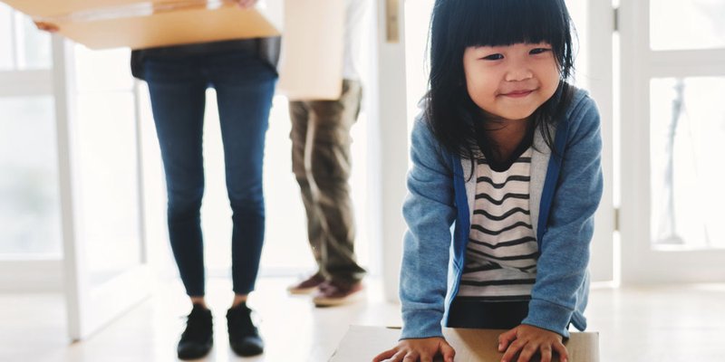 Family moves into new home with toddler girl helping with a tiny box