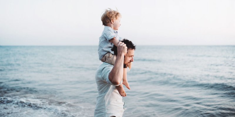 Dad gives his son a piggyback ride with lake in the background