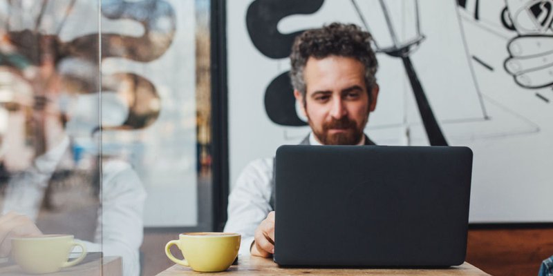Man working in a modern coffee shop in his laptop