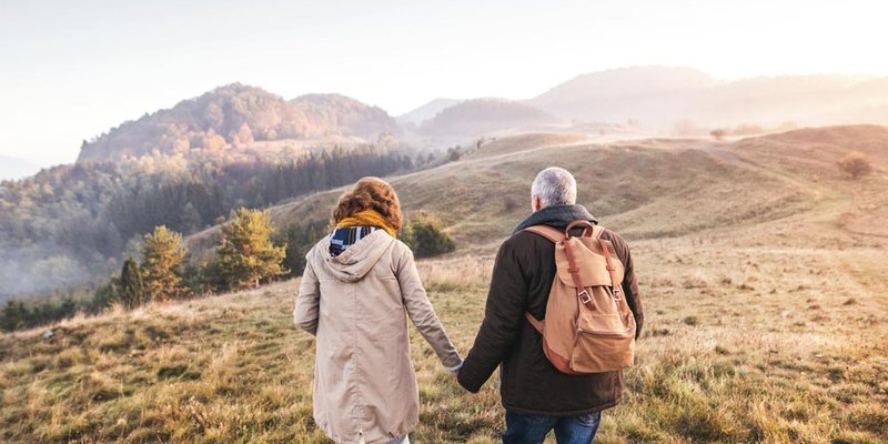 A senior couple walk up a foggy hillside