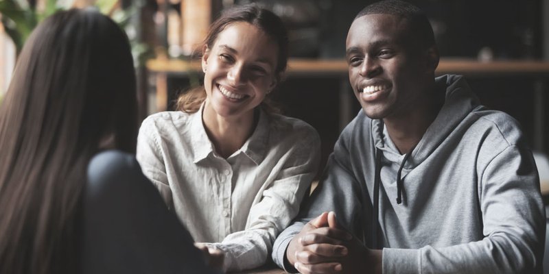 A happy young couple smile at a realtor