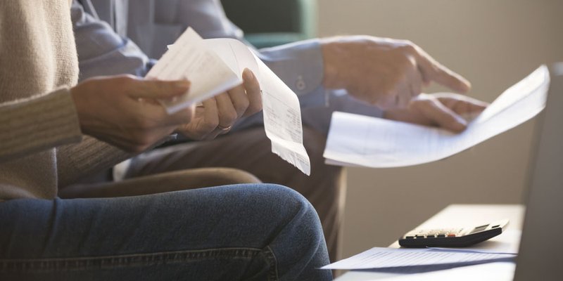 A close-up of hands holding documents and receipts