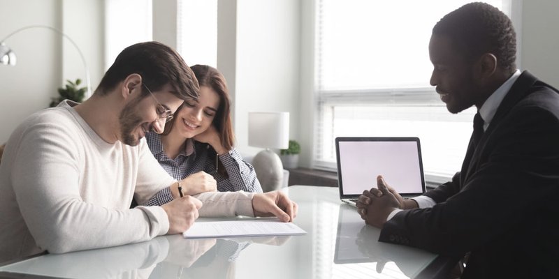 A realtor helps a young couple with paperwork