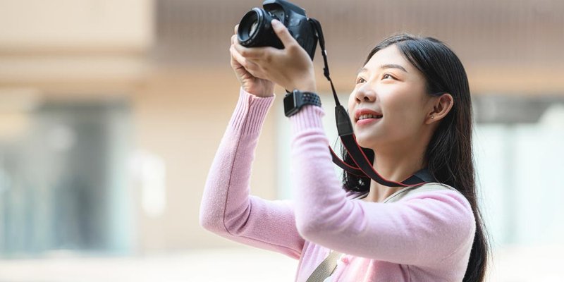 A young woman holds up her camera to take a picture