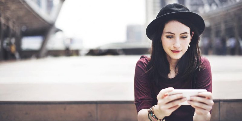 A women sits on a set of steps and uses her phone