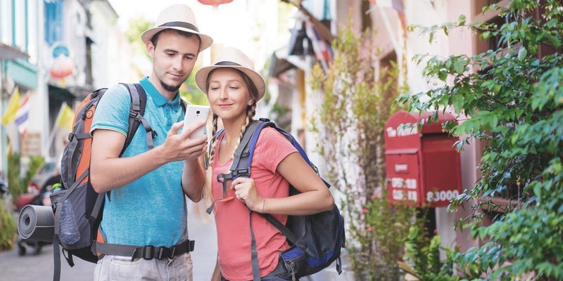 A young couple walk with their backpacks down a street