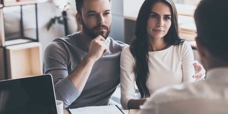A young couple speak with a broker or advisor