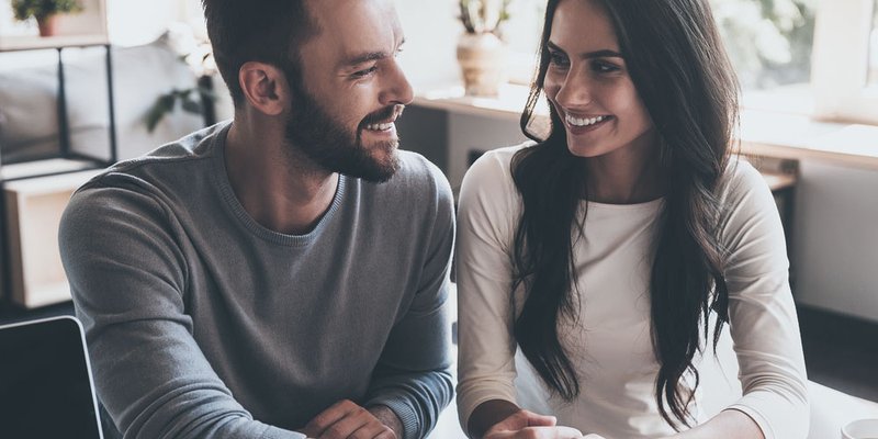 A young couple smile and look toward each other