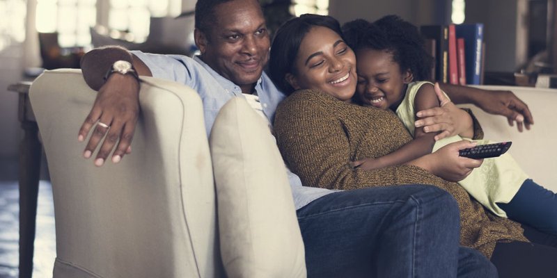 A family cuddling up on the couch to watch TV
