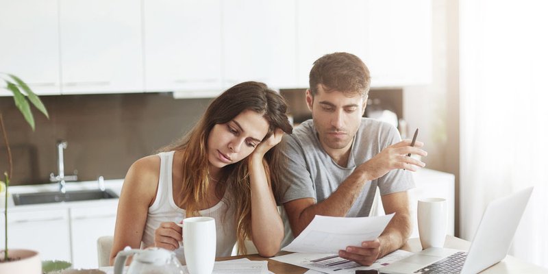 A couple look frustrated at their many bills