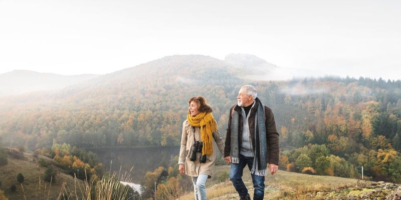 A senior couple walk up a foggy hillside