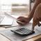 African woman holding paper bills using calculator, close up vie