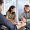 Mature couple discussing in meeting with bank manager for loan. Mature man and woman looking at each other while they are on a visit with a businessman. Happy couple talking amongst themselves