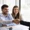 Cheerful young couple shaking hands with African American lawyer, broker, consultant, real estate agent, thanking for consultation. Positive business partners giving handshake at meeting, smiling