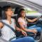 A Young black teenage driver seated in her new car with her mother